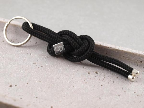 Achterknoten Schluesselanhaenger aus schwarzem Segeltau mit silbernem Wuerfel mit Gravur